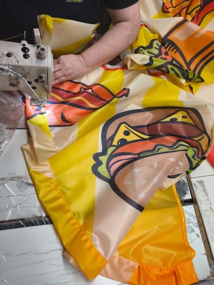 Couture des finitions d'une voile de drapeau publicitaire à l'atelier