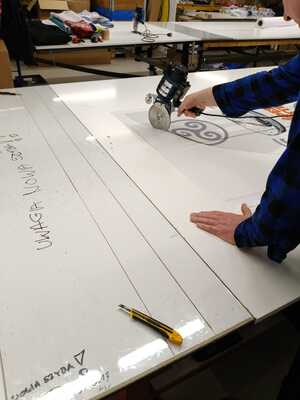 Découpe d'une voile d'oriflamme personnalisée sur la table de coupe de l'atelier
